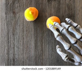 Ghoulish Skeleton Hand Reaching For Candy Corn Orange And Yellow Cupcakes