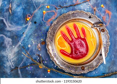 Ghoul's Orange Punch With Bloody Ice Hand In A Glass Bowl On Dark Halloween Background