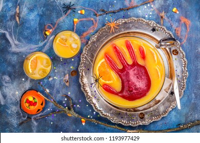 Ghoul's Orange Punch With Bloody Ice Hand In A Glass Bowl On Dark Halloween Background