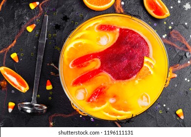 Ghoul's Orange Punch With Bloody Ice Hand In A Glass Bowl On Dark Halloween Background