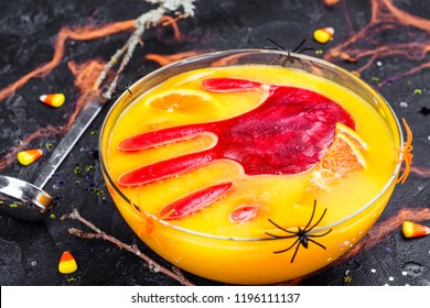 Ghoul's Orange Punch With Bloody Ice Hand In A Glass Bowl On Dark Halloween Background