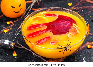 Ghoul's Orange Punch With Bloody Ice Hand In A Glass Bowl On Dark Halloween Background