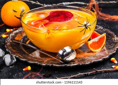 Ghoul's Orange Punch With Bloody Ice Hand In A Glass Bowl On Dark Halloween Background