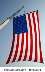 A Giant American Flag Is Suspended High From The Boom Of A Crane