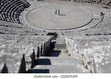 Giant Ancient Greek Theatre In Epidaurus Viewed From The Upper Level With Two People Standing In The Center Of Stage, Greece