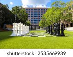 a giant black and white chess set on lush green grass surrounded by lush green and autumn colored trees near buildings at Lenox Park in Brookhaven Georgia USA	