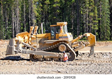 A Giant Bull Dozer Moving Rocks During Road Construction In A Forested Area.