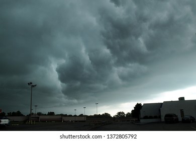 Giant Dark Ominous Thunderstorm Clouds In The Sky Overhead Up Above A Shopping Mall, Strip Mall Parking Lot 