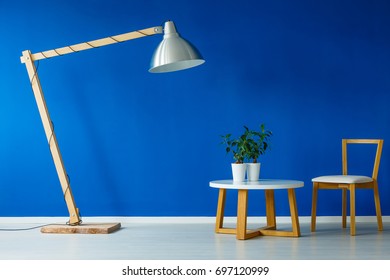 Giant Lamp Standing Over A Small Wooden Table With Two Plants And A Chair In A Scandinavian Design Day Room