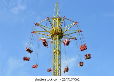 
A giant multi-colored carousel in an amusement park, against a blue sky. - Shutterstock ID 2147174061