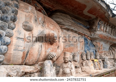 Giant sculpture of Buddha in Nirvana with statues of disciples or followers in front at Dazu Rock Carvings at Mount Baoding or Baodingshan in Dazu, Chongqing, China. UNESCO World Heritage Site.