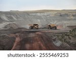 Giant sized yellow coal mining loader trucks passing each other inside an open pit coal mine in the Powder River Basin of Wyoming
