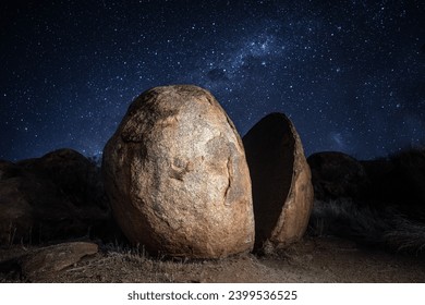 Giant split rock with a sky fall of stars behind it at Karlu Karlu (the Devils Marbles) in Northern Territory, Australia