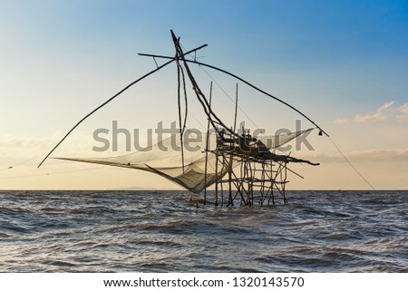 Giant square dipnets for trapping fish in the wavy sea on blue sky background in the morning