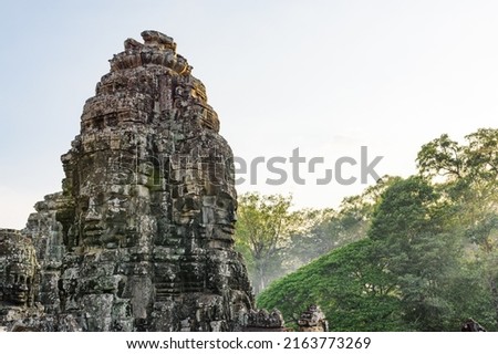 Giant stone face of ancient Bayon temple. Bayon temple nestled in Angkor Thom, Siem Reap, Cambodia. Angkor Thom is a popular tourist attraction.