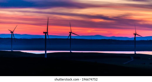 Giant wind turbines standing up the hills near the waterside of Lake George, NSW, Australia