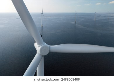 Giant wind turbines tower above the calm sea, harnessing nature's energy as the sun sets, painting the sky with warm hues in the Netherlands, close up drone view at a windmill turbine - Powered by Shutterstock