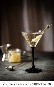 Gibson alcohol cocktail with martini and onions in martini glass. Decorated cocktail on dark background