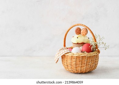 Gift Basket With Painted Easter Eggs, Flowers And Cake On Light Background
