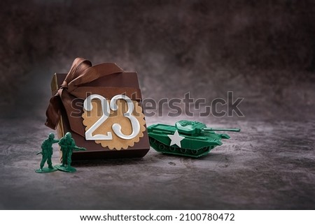 gift box with bow, 23 number, tank and soldiers toys on abstract dark background. Present for day of defenders of fatherland, 23 february holiday concept. gift for man