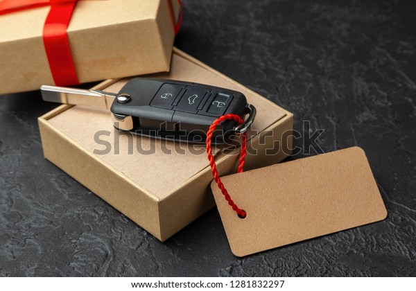 Gift box with car keys with remote control\
alarm system with red ribbon bow and\
label