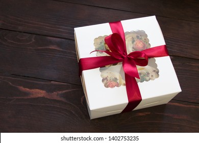 Gift Box with  cupcakes .White box with red bow on wooden board.Sweet present