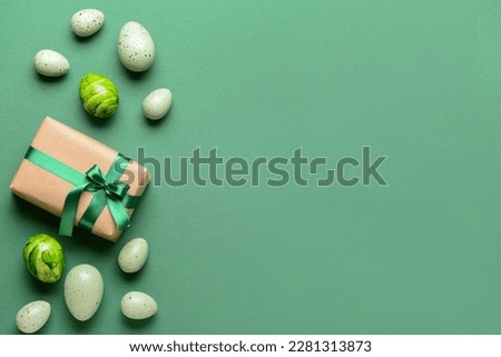Gift box with Easter eggs on green background