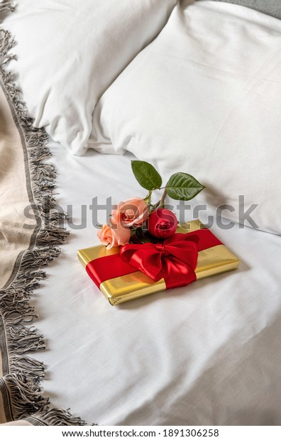 A gift box\
and flowers lies in bed early in the morning. Content for\
honeymooners and lovers for Valentine\'s\
Day.
