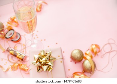 Gift Box With Golden Bow On Pink Coral Background With Stars And Sparkles. Festive Concept Copyspace Top Horizontal View. Sticky Tape, Christmas Balls, Golden Ribbon