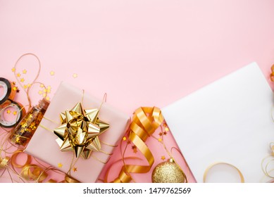 Gift Box With Golden Bow On Pink Coral Background With Stars And Sparkles. Festive Concept Copyspace Top Horizontal View. Sticky Tape, Christmas Balls, Golden Ribbon