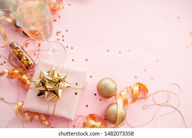 Gift Box With Golden Bow On Pink Coral Background With Stars And Sparkles. Festive Concept Copyspace Top Horizontal View. Sticky Tape, Christmas Balls, Golden Ribbon