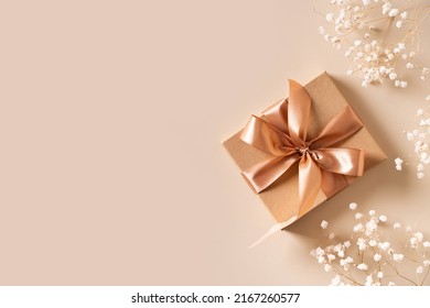 Gift box with golden ribbon and dry grass and flowers on beige background flat lay, top view, copy space - Powered by Shutterstock