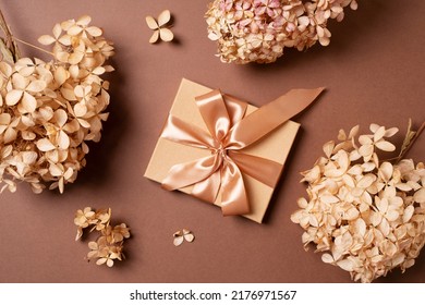 Gift box with golden ribbon and dry grass and flowers on brown background flat lay, top view, copy space - Powered by Shutterstock