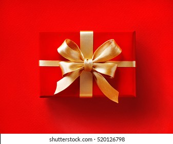 Gift Box With Golden Ribbon On Red Background. Close Up. Top View. High Resolution Product