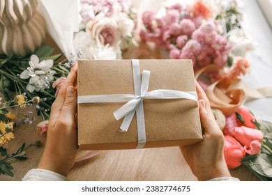 Gift box in hands with flowers at home. - Powered by Shutterstock