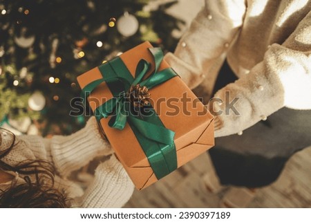 Gift box in the hands of mother and daughter, Christmas mood.