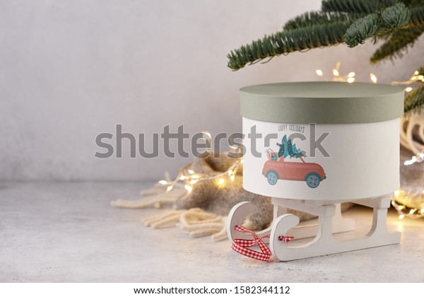Gift box with holiday car\
print under Christmas tree on wool blanket and lights background,\
copy space