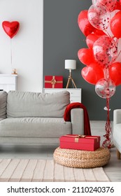 Gift box near sofa in living room decorated for Valentine's day