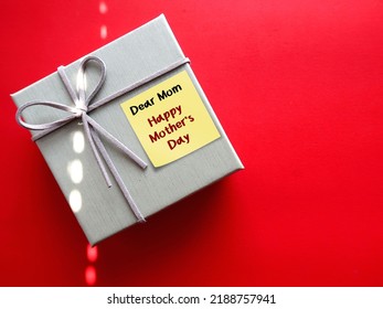 Gift box on red copy space baclground with handwritten text DEAR MOM, HAPPY MOTHER'S DAY, concept of express gratitude, honour mother unconditional love and make mom feel special