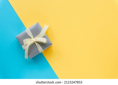 Gift box on yellow and blue background. Happy birthday, Valentines day, Women's day concept. Top view, flat lay, copy space.