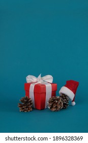 gift box, pine cones, christmas ball and Santa hat isolated on blue background. Christmas concept. Image contains copy space