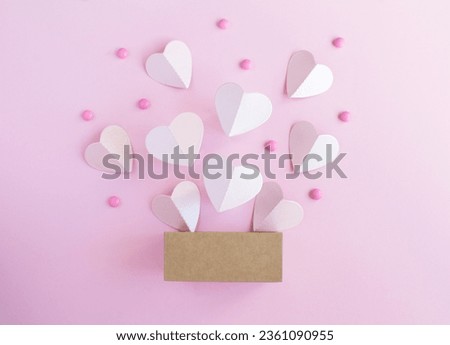 Gift box with pink paper hearts on the pink background. Close-up. Top view.