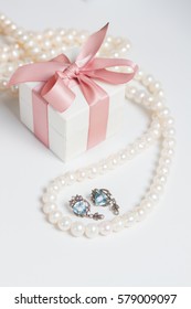 Gift Box With Pink Ribbon With Jewellery On White Table