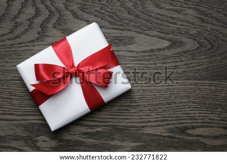 gift box with red bow on wood table, top view