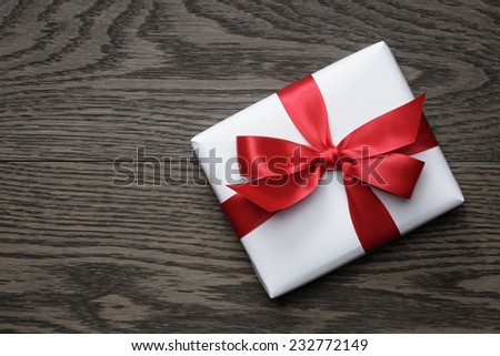 gift box with red bow on wood table, top view