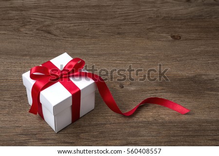 gift box with red bow on rustic table, christmas or another celebration