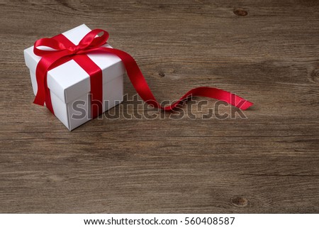 gift box with red bow on rustic table, christmas or another celebration