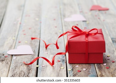 Gift box with red bow ribbon and paper heart on wooden table for Valentines day. - Powered by Shutterstock