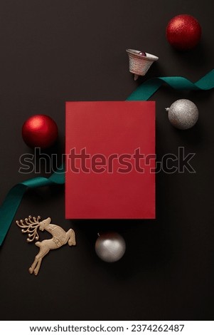 A gift box in red color placed on black background with a ribbon, reindeer, bell and few baubles. Christmas has never failed to attract people with various ways to celebrate in different nations