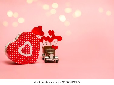 Gift Box And Retro Car With Paper Hearts On A Pink Background. Valentine's Day Concept, Anniversary, Mother's Day And Happy Birthday Greeting, Copyspace, Close Up